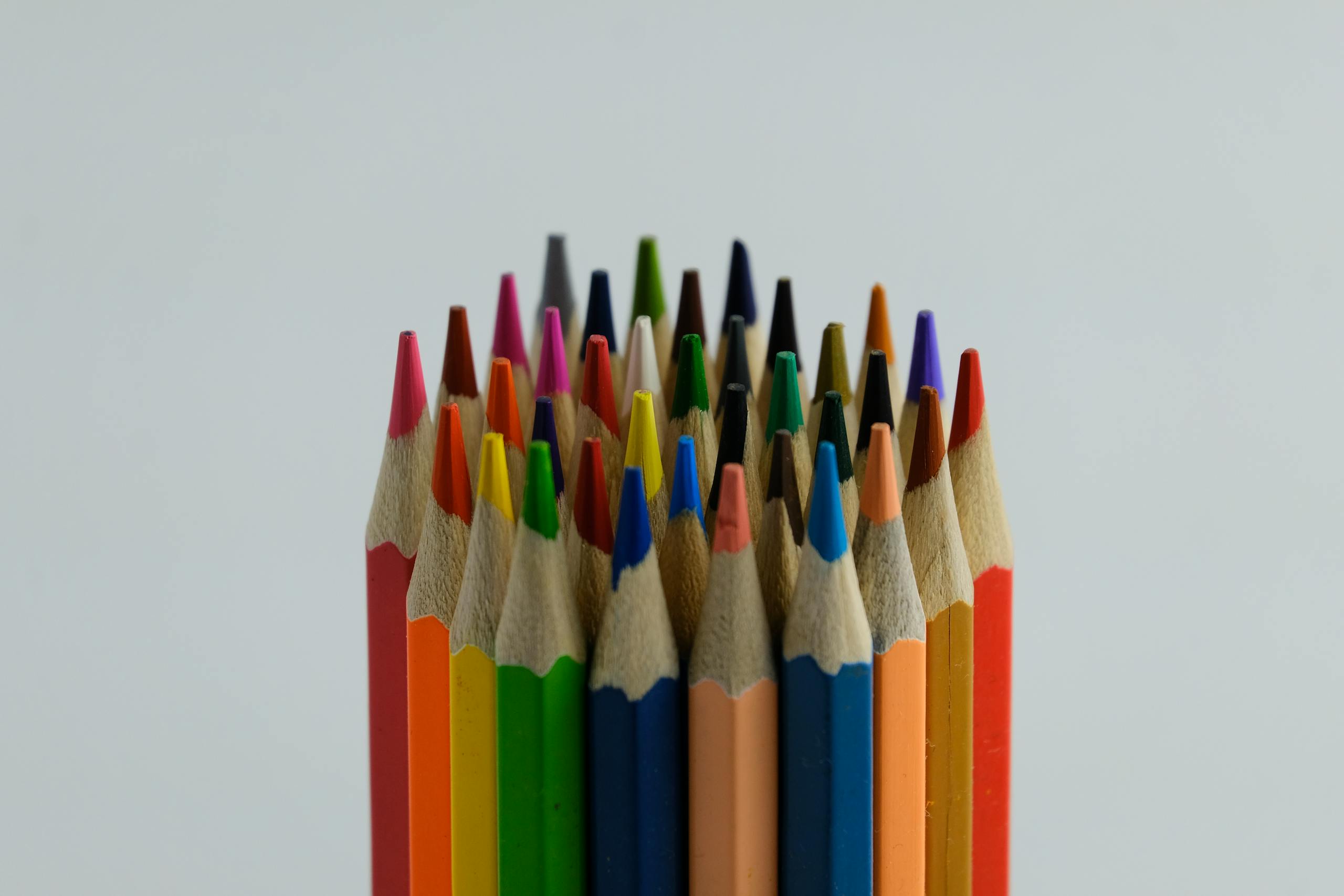 Close-up of assorted colored pencils arranged vertically, showcasing vivid hues on a white backdrop.